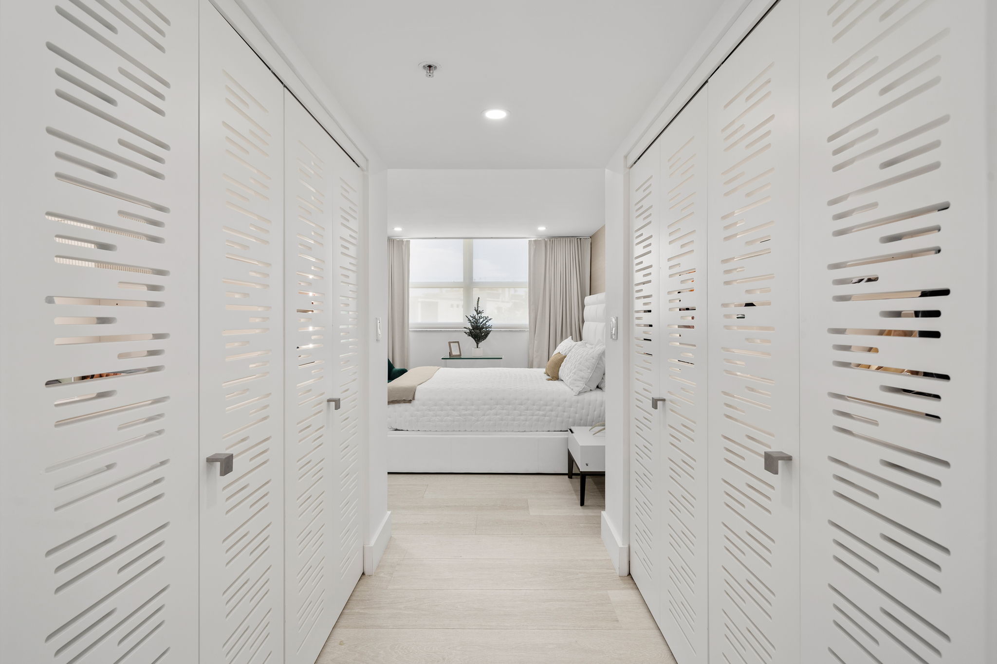 Hallway with custom laser-cut closet doors leading to primary bedroom